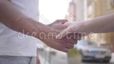 中东男人和高加索女人在城市背景特写面前握手。 爱情，友谊，浪漫